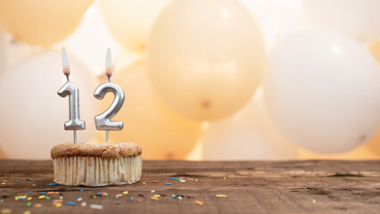 Happy birthday card with candle number 12 in a cupcake against the background of balloons. Copy...