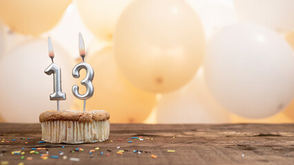 Happy birthday card with candle number 13 in a cupcake against the background of balloons. Copy...