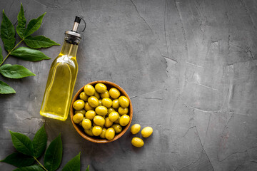 Bottle of olive cooking oil with green olives in bowl