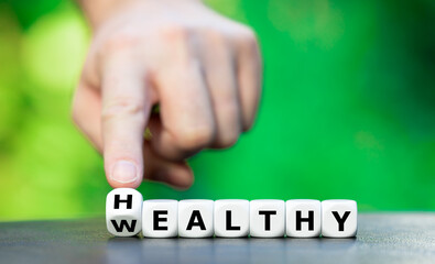Hand turns dice and changes the word wealthy to healthy.