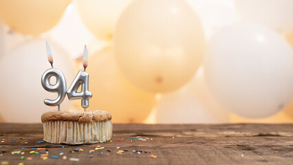 Happy birthday card with candle number 94 in a cupcake against the background of balloons. Copy...