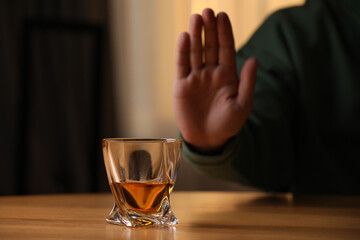 Man refusing to drink whiskey indoors, closeup. Alcohol addiction treatment