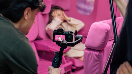 Photographer taking shots of a young woman in pink studio