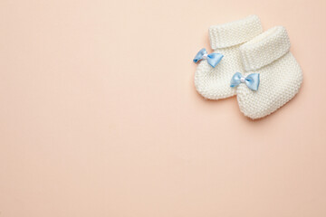 Knitted baby booties on light pink background, flat lay. space for text