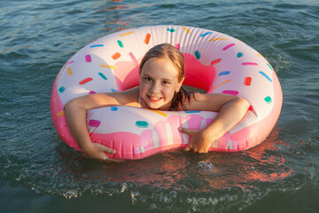 Happy child girl in swimsuit with swimming ring on the sea