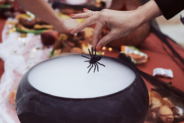 Many hand put near the smoking cauldron during halloween celebration