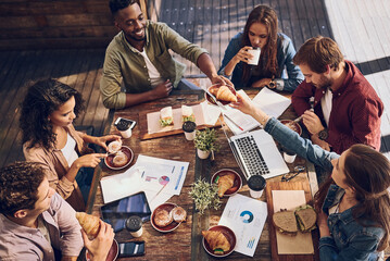 Catching up on statistics while enjoying a good bite. Shot of a group of creative workers having a...