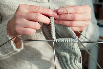 Female hands hold knitting needles and knit a sock. Handmade and hobby concept. Close up.