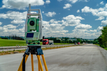 Surveyors equipment (theodolite or total positioning station) on the construction site of the road, highway or building with construction machinery background