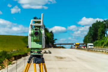 Surveyors equipment (theodolite or total positioning station) on the construction site of the road,...