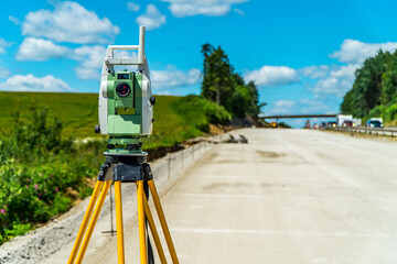 Surveyors equipment (theodolite or total positioning station) on the construction site of the road, highway or building with construction machinery background
