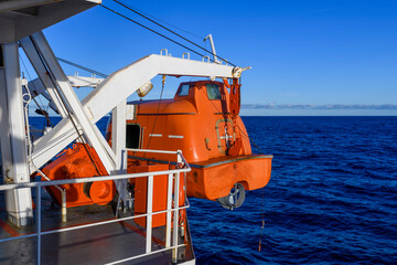 Lowering orange totally enclosed lifeboat to water. Abandon ship drill. Lifeboat training. Man over...
