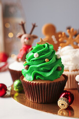 Tasty Christmas tree cupcake and baubles on white table