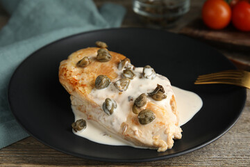 Delicious chicken fillet with capers and sauce served on wooden table, closeup