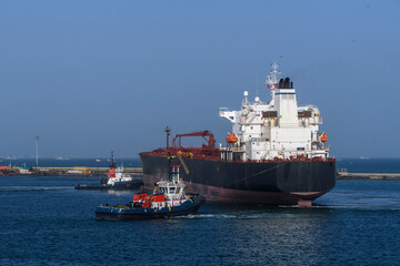Cargo vessel going to sea from port with tug assistance. Bulk carrier. Dry cargo ship.