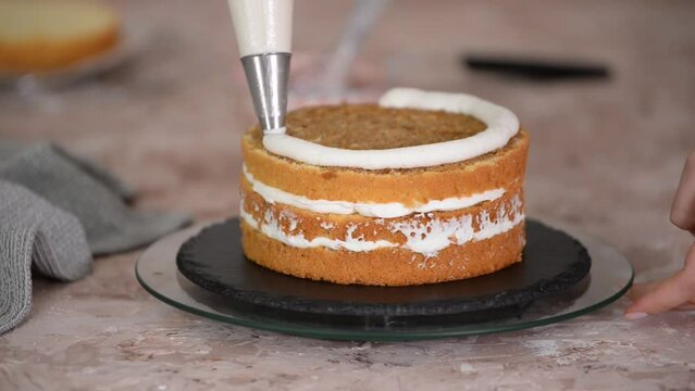 A woman spreads cream on top of the cake layers.