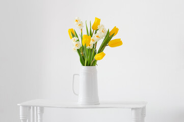 white and yellow spring flowers  in vase on white background