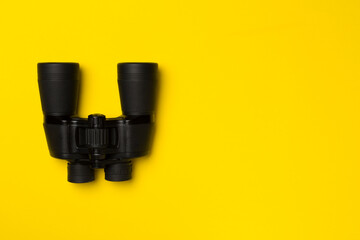 Black binoculars on color background. Top view
