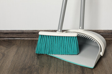 Plastic broom with dustpan on wooden floor indoors