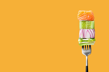 Close-up of fork with food on it: delicious fillet salmon, cucumber, onion, green salad on orange...