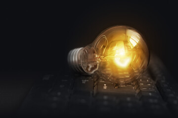 Light bulb glowing on pc keyboard, idea of business ​​inspiration, innovation idea concept.