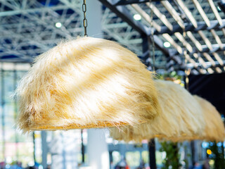 An unusual shaggy lampshade lit by sunlight from the window is located in the interior of the cafe....