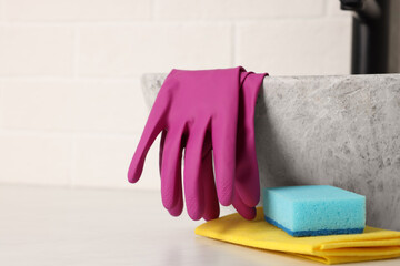 Sponge, rag and rubber gloves near sink in bathroom. Space for text