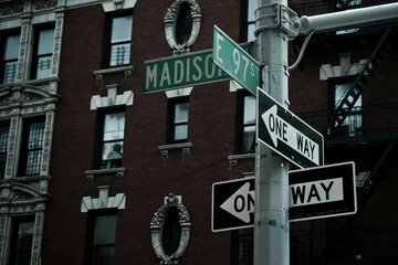 One way direction signs in Madison street with the 97 street in New York. New York stile building...