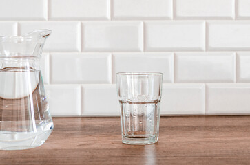 Jug and glass with water on white background