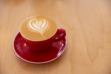 Latte in a red cup with milk frothed milk design