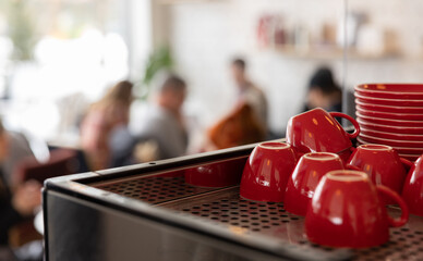 Coffee mugs on top of a coffee machine with cafe surrounding