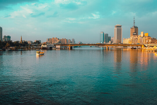 Cairo Egypt December 2021 View of the amazing Nile river at sunrise, boats anchored on the shores. Bright blue river and sky colors. Skyscrappers in the distance