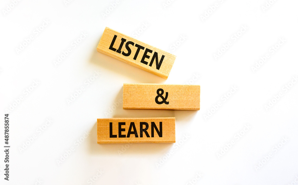 Poster Listen and learn symbol. Concept words Listen and learn on wooden blocks. Beautiful white table white background. Copy space. Business, educational and listen and learn concept.