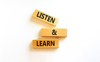 Listen and learn symbol. Concept words Listen and learn on wooden blocks. Beautiful white table...