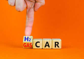 Gas or H2 hydrogen car symbol. Businessman turns a wooden cube and changes words Gas car to H2 car. Beautiful orange table orange background copy space. Business and gas or H2 hydrogen car concept.