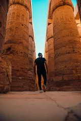 Foto op Plexiglas Vertical shot of man tourist walking around the massive pillars in luxor temple in egypt. Ancient egyptian pillars stand here after thousands of years, available for people to visit © Antonio