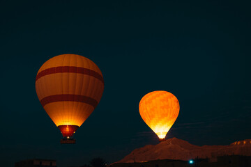 Two yellow balloons illuminated by flame torches flying in the air in the luxor egypt area. Early...