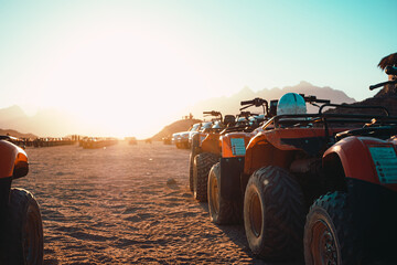 View of several atv quad bikes parked inline in the middle of a desert near hurghada. Sunset hour with the sun shining straight at the camera