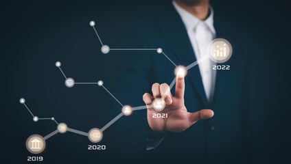 Businessman touch line arrow with number 2022 on the graph chart of stock market ,Technology Process System Business with Investment and stock market concept gain and profits with faded number charts.