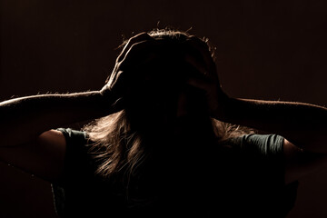 Half face of unrecognizable woman in shadow shrouded in darkness, victim of domestic violence