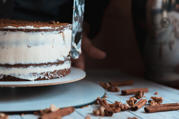 The pastry chef levels the cake with cream