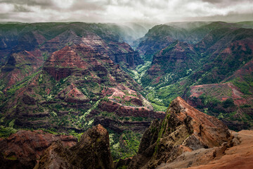 Stunning overlook at Waimea Canyon State Park in Kauai, Hawaii with lush green hills and a winding...