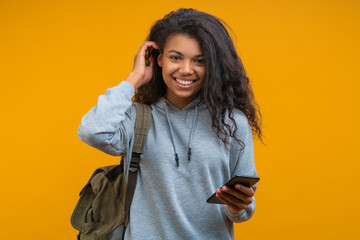 Portrait of cute smiling casually dressed young student girl holding mobile phone in hand and...