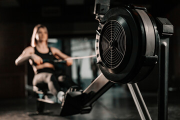 Healthy woman doing exercises on fitness machine in gym. Selective focus on machine.