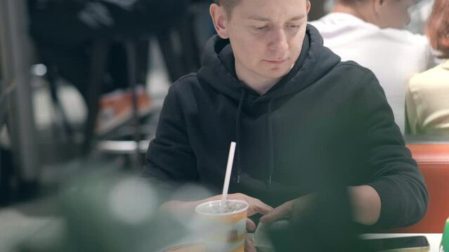 Man student eats nuggets, french fries and drinks cola at McDonalds fast food restaurant. Unhealthy nutrition, snacks, junk food. 26aug2021 St-Petersburg Russia.