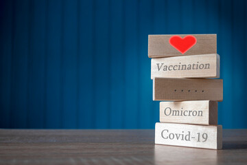 Covid-19, Omicron, vaccination, health are written in embossed wooden rectangles . The...