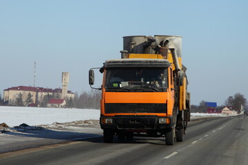 Fototapeta na wymiar Yellow loaded small truck on suburban winter road in Europe. Front view closeup. Transportation logistics.