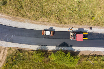 Fototapeta premium Aerial view of new road construction with asphalt laying machinery at work
