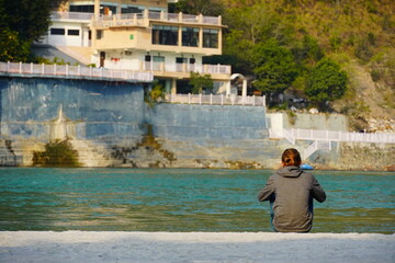Alone man is waiting for someone near water and building
