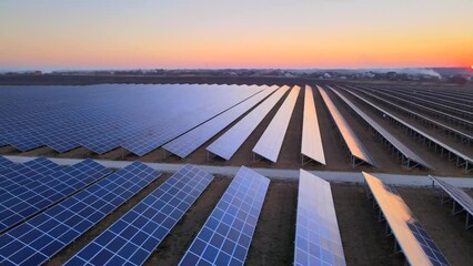 Aerial drone view of large solar panels at a solar farm at bright sunset in early winter. Solar cell power plants